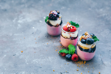 Assortment of creamy gourmet strawberry desserts layered in decorative patterns in individual glass containers