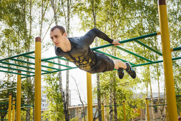 Fitness man at the bar. Exercising outdoors in the Park. Street workout.