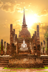Big Buddha and pagoda of Wat Sa Si (temple) against a vibrant sunset. Sukhothai Historical Park, Thailand. Unesco World Heritage Site