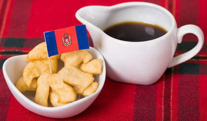 Delicious ecuadorian pristinos piled up in bowl, traditional andean pastry, cup of coffee siting on table, Quito flag planted inside pastries