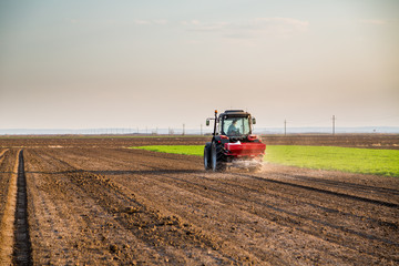 Obraz premium Farmer fertilizing arable land with nitrogen, phosphorus, potassium fertilizer