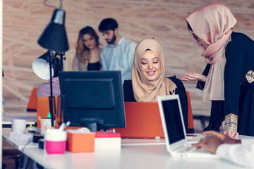 Two woman with hijab working on laptop in office.