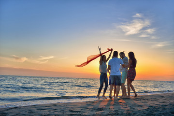 Fototapeta premium group of happy young people dancing at the beach on beautiful summer sunset