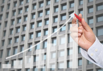 Businessman to point in peak of Business graph on abstract Skyscraper wall background.
