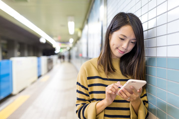 Woman working on cellphone in train station