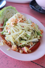 Raw mango salad in white dish.