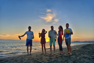 Group of happy young people is running on background of sunset beach and sea