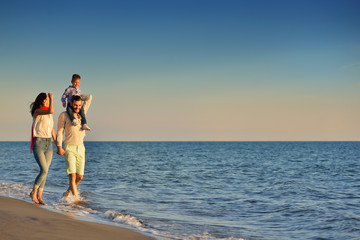 happy young family have fun on beach run and jump at sunset