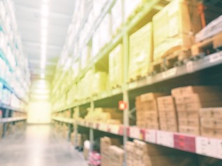 Blurred warehouse or storehouse with The boxes on high shelves stocked. Motion blur effect. Bright sunlight as background.