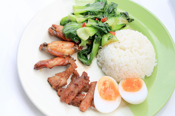 stir fried vegetables, Hard-boiled egg, Fried pork and Fried chicken wings with thai jasmine rice on dish. Thai food.