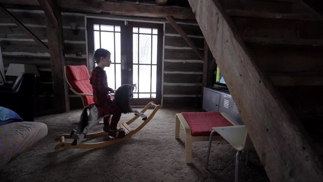 kid on rocking horse inside an old barn converted in home in canada lumber winter snow