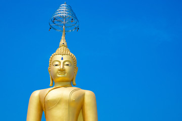 Golden Buddha statue against blue sky.