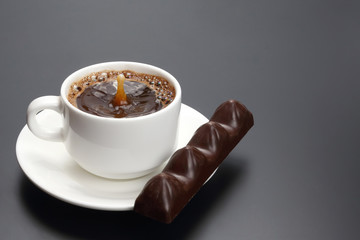 white cup with black coffee and chocolate on the saucer