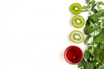 Obraz na płótnie Canvas Detox diet & healthy food & drink & healthy llifestyle: Orange green fruit salad & herbs. Grapes cherry juice kiwi fruits & mint herb. Top view. White wooden background. Free space text layout..