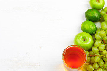 Detox food & drink healthy lifestyle concept: healthy sweet green & orange fruits & juices. Orange apple grapes juices & lime lemon kiwi Top view. White wooden background. Free space text layout.