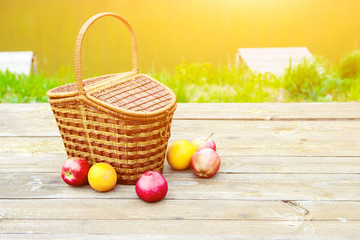 Picnic on the nature in the forest near the river. Wooden table and fruit basket
