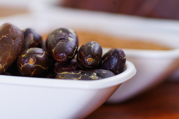 Close up of a dark dry cocoa bean inside of a white bowl