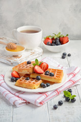 Waffles with fresh berries on rustic wooden background, selective focus