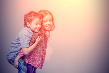 Girl in a red blouse with a boy in a blue shirt on her back