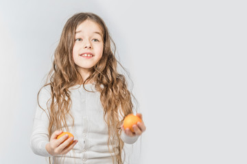 Cute smiling girl juggles with mandarins on a gray background. Isolated