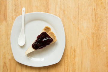 Blueberry cheese cake on white dish with spoon on wooden table background