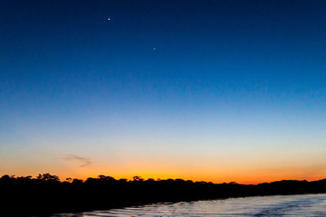 View of a sunset over Amazon river in Brazil. Planets Venus and Jupiter are also visible. © Matyas Rehak