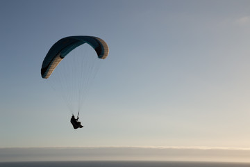 A single paraglider floats in the sky above the Pacific Ocean in the San Francisco Bay Area, California