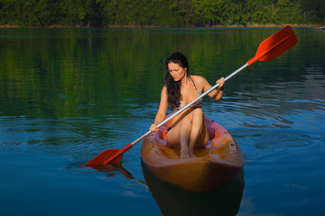 A girl on a kayak. Dawn on Lake Cheolan. Khao Sok National Park in Thailand The girl on the boat. rowing.