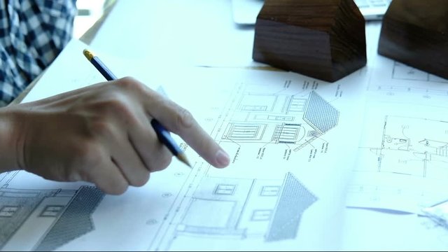 young architect working on real estate project at workplace. Male engineer hand working with living house blueprint at office. Business, people, construction and building concept