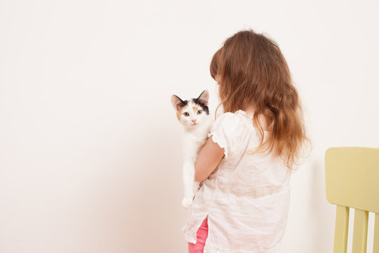 A child playing with a white kitten