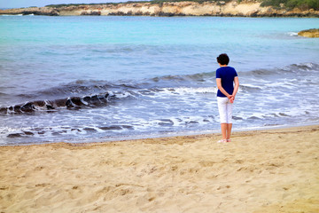 Young woman standing on the sand by the sea