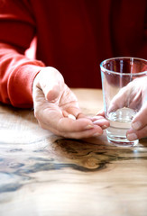 Medical pill on the wrinkly hand of an old man
