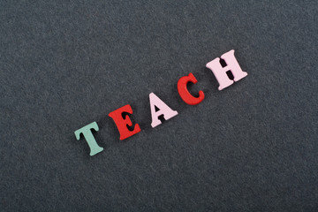 TEACH word on black board background composed from colorful abc alphabet block wooden letters, copy space for ad text. Learning english concept.