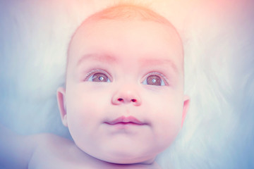 Cute baby lying on a white fur in the sunlight