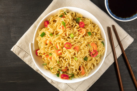 Instant noodles with vegetables, sauce, chopsticks, copy space