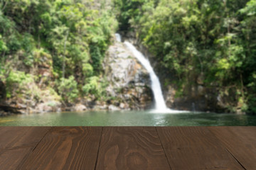 Wooden board empty table in front of blurred waterfall backgroun