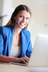 Portrait of beautiful business woman working at her desk with headset and laptop.
