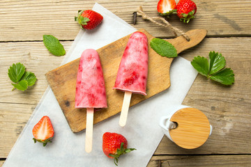 Fresh homemade strawberry ice cream on wooden background. Organic and vegan popsicles