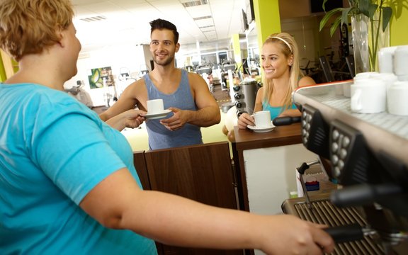 Overweight waitress serving coffee in gym