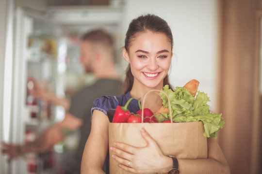 Young couple in the kitchen , woman with a bag of groceries shopping