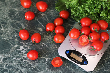 Fresh tomatoes on kitchen scales weighing