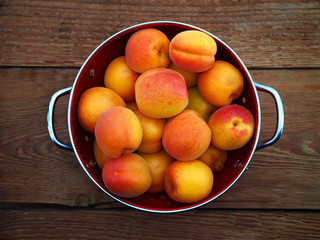 Apricot fruit in bowl on wooden background. Top view.