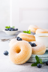 Doughnuts with powdered sugar, cup coffee and fresh blueberries on light gray background. Selective focus. Copy space.
