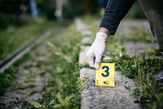 Placing the crime scene marker on the ground near train track