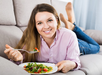 Obraz na płótnie Canvas Young girl trying tasty greenery salad at home