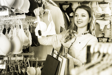 Pretty girl shopper examining bras in  shop