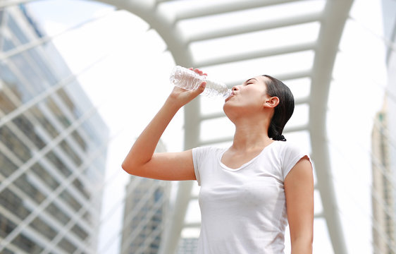 Thirsty woman drinking water in public area.