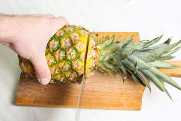 Man cutting pineapple on a wooden board