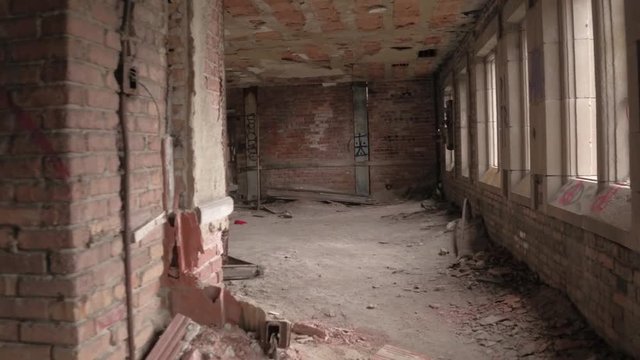 FPV CLOSE UP: Exploring decaying abandoned building with crumbling walls and collapsing ceilings. Walking along the dark narrow corridor past creepy dark rooms in ruined disintegrating dangerous house