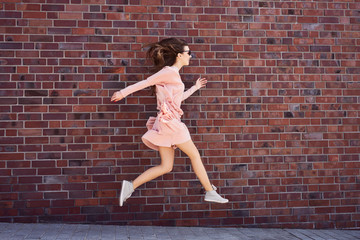 Fototapeta na wymiar Joyful young woman jumping on the sidewalk